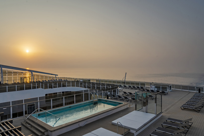 Zen Pool auf dem Sonnendeck der MSC World Europa bei Sonnenuntergang, mit Liegen und Blick auf das Meer