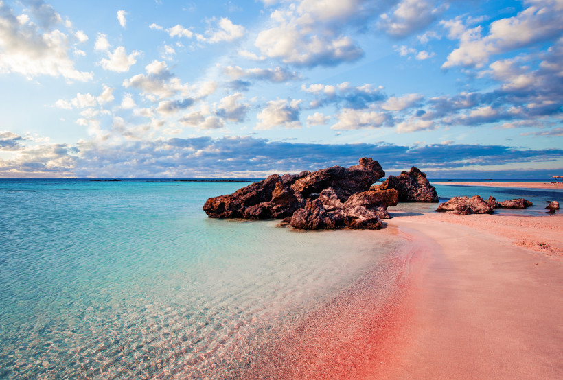 Elafonisi Strand mit rosa Sand, türkisfarbenem Wasser und Felsen im seichten Meer