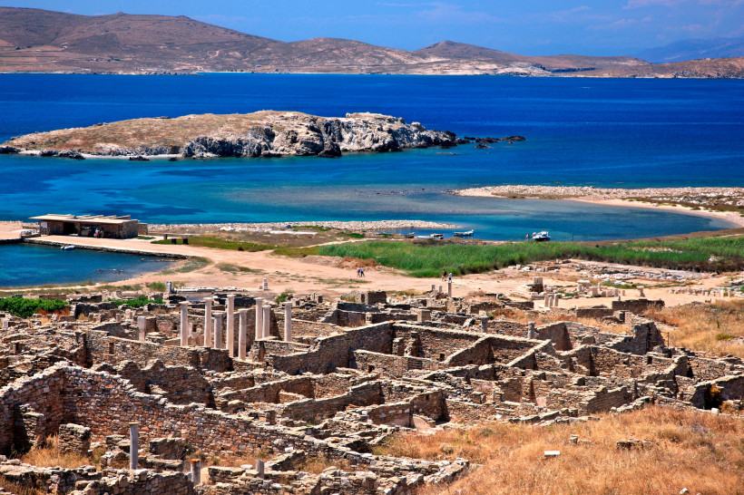 Mykonos - Delos Panoramablick auf die Ruinen der Insel Delos mit antiken Mauern und Säulen vor dem tiefblauen Meer