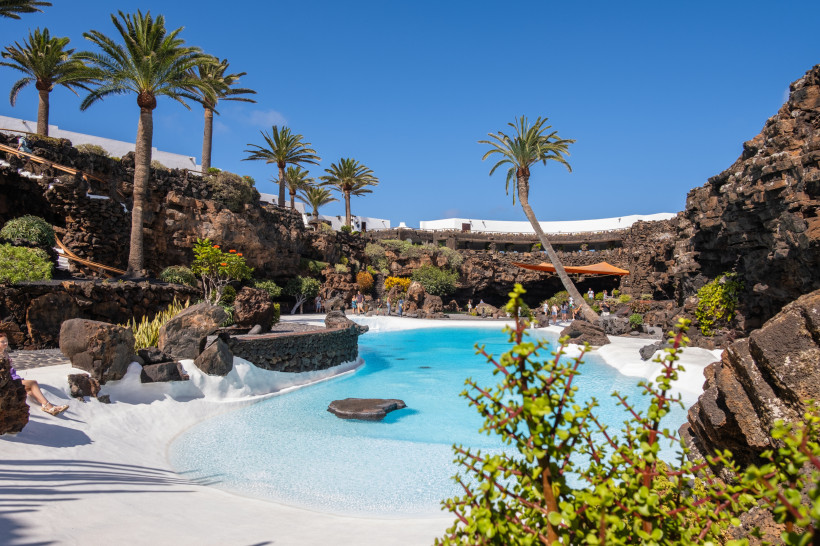 Jameos del Agua Lanzarote – Traumhafte Vulkanlandschaft mit türkisfarbenem Pool Jameos del Agua Lanzarote mit türkisblauem Pool, Palmen und vulkanischen Felsformationen im Stil von César Manrique