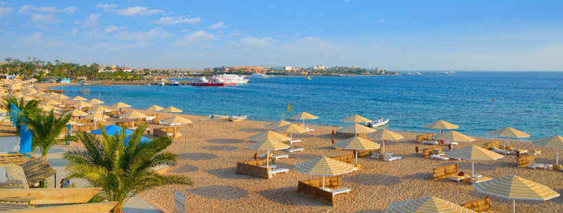 Strandpanorama in Hurghada mit Sonnenschirmen und kristallklarem Meer Weiter Sandstrand in Hurghada mit hellen Sonnenschirmen, Liegen und Blick auf das ruhige blaue Meer
