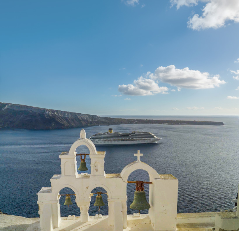 Costa Fascinosa vor Santorini Kreuzfahrtschiff Costa Fascinosa vor der Küste von Santorini, im Vordergrund Kirchenglocken und Kreuz