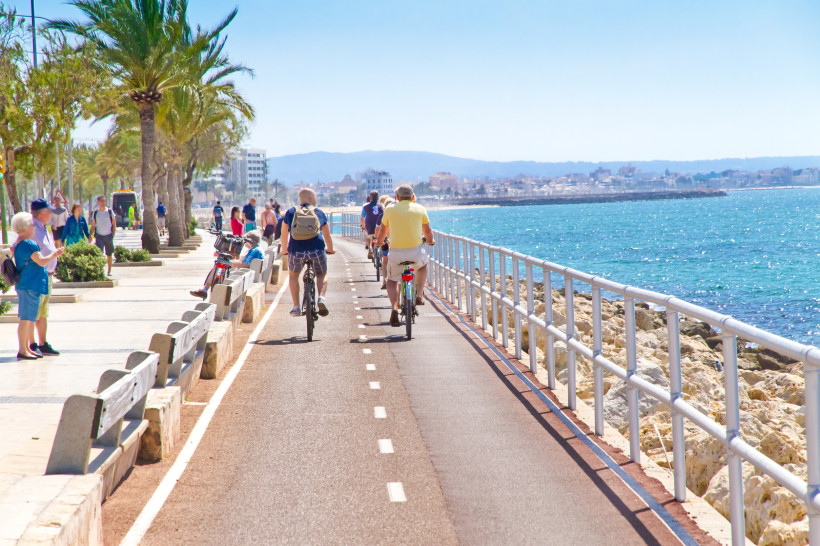 Fahrradweg an der Uferpromenade in Palma de Mallorca mit Radfahrern, Fußweg und Meerblick