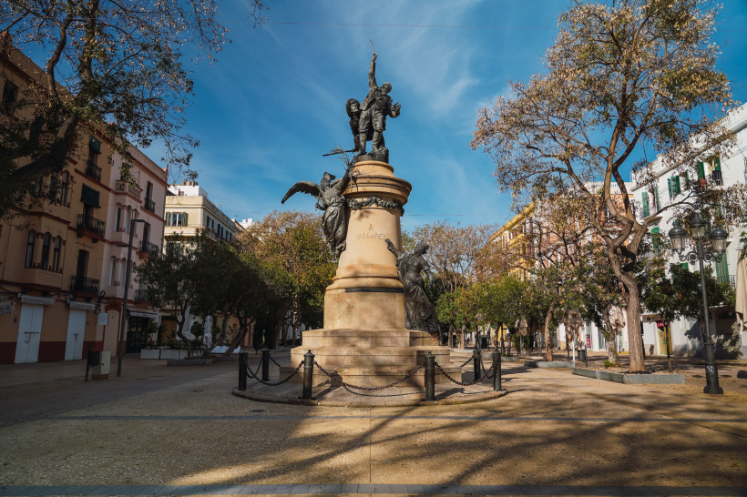 Denkmal auf einem Platz in Ibiza-Stadt, umgeben von Bäumen und Wohnhäusern