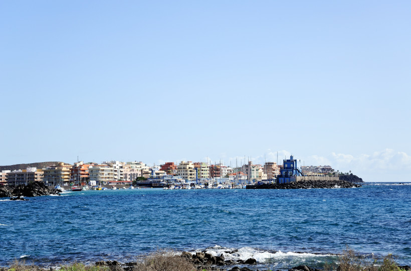 Blick über das Meer auf den Hafen und die Uferbebauung von Las Galletas