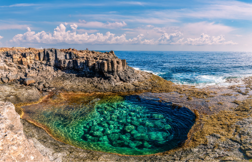 Felsküste bei Caleta de Fuste mit natürlichem Meerwasserbecken im Vordergrund und Atlantik im Hintergrund