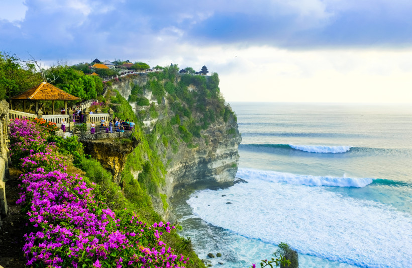 Uluwatu, Bali Aussichtsplattform am Uluwatu-Tempel auf Bali mit Besuchern, bunten Blumen und steilen Klippen über dem Meer