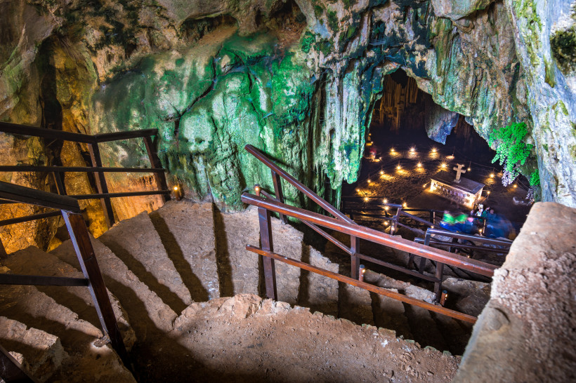 Melidoni-Höhle: Treppenabgang zur beleuchteten Höhlenkammer mit Altar und Kreuz Steintreppe mit Geländern in der Melidoni-Höhle, Blick in die beleuchtete Hauptkammer mit Altar und Kreuz