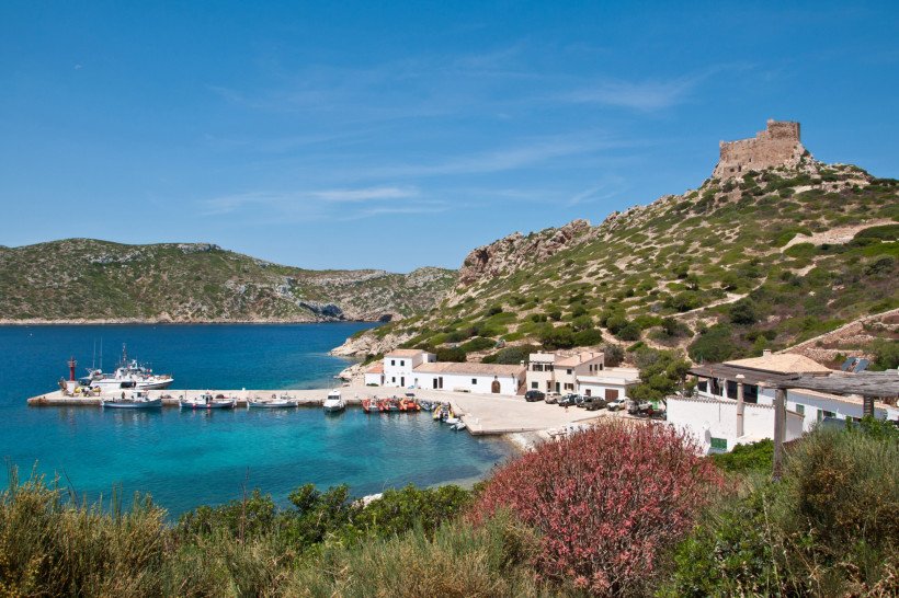 Hafenbucht im Archipiélago de Cabrera mit Booten, weißen Gebäuden und Festung auf einem Hügel
