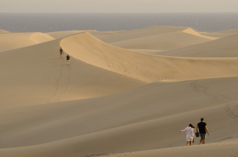 Sanddünen von Maspalomas mit Blick auf den Atlantik, mehrere Personen gehen über die Dünenkämme