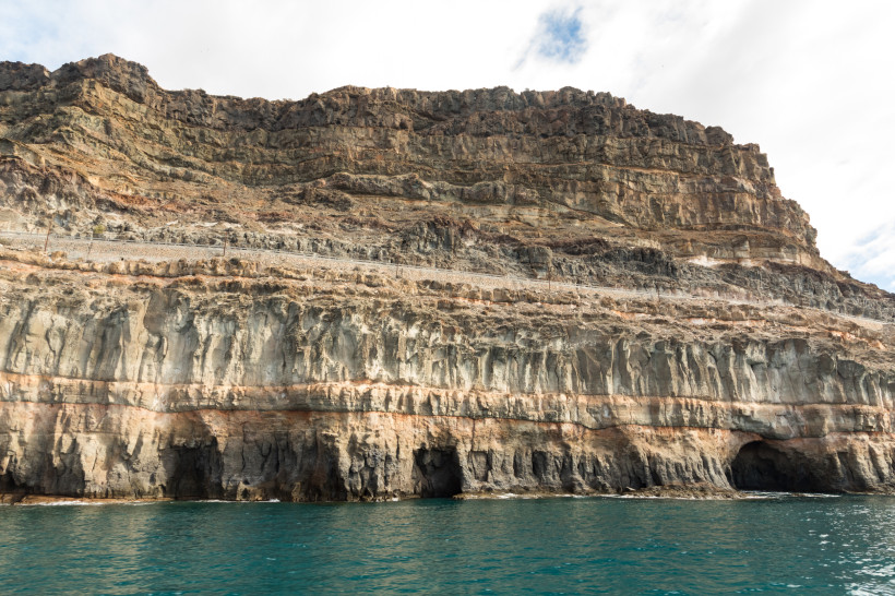 Küstenklippe auf Gran Canaria mit deutlich sichtbaren Schichten vulkanischen Gesteins über dem Meer