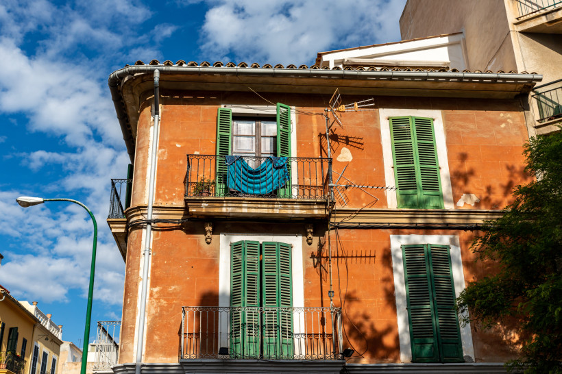 Fassade eines Hauses in Santa Catalina mit grünen Fensterläden und Balkonen unter blauem Himmel