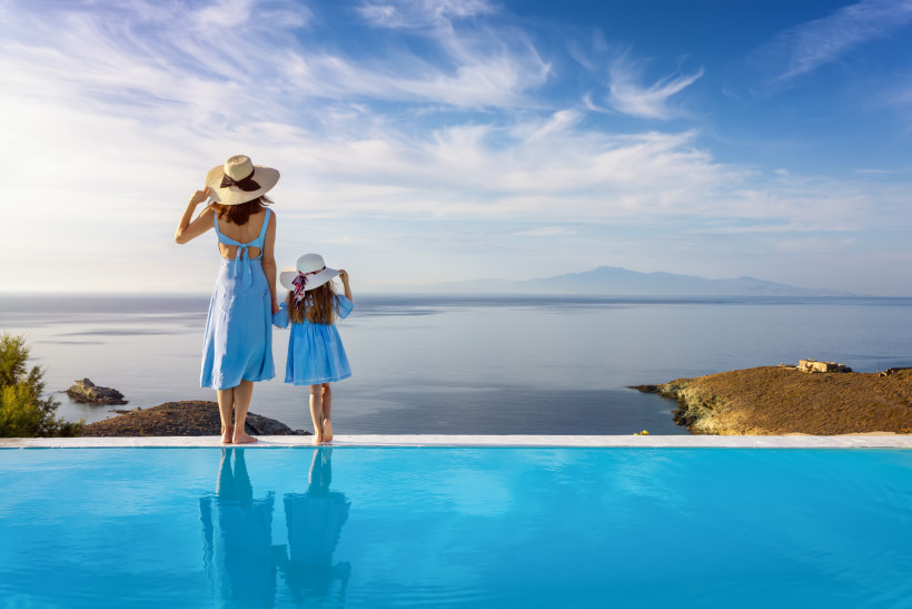 Mutter und Kind stehen am Infinity-Pool eines Premium-Resorts mit Blick auf das Meer – komfortabler Familienurlaub mit Ruhe, Platz und hochwertiger Hotelanlage
