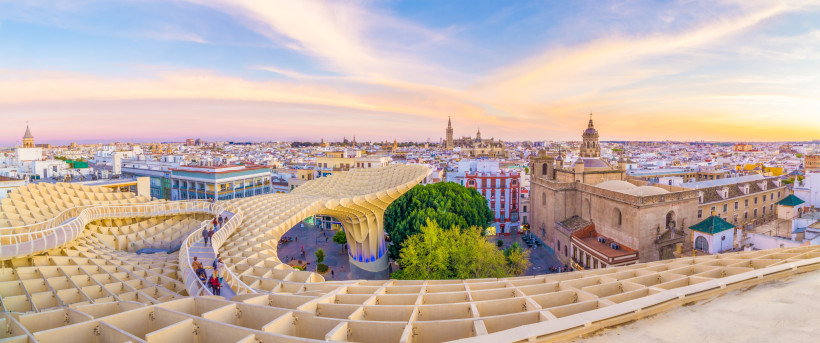 Panoramablick auf Sevilla bei Sonnenuntergang mit dem modernen Holzdach Metropol Parasol im Vordergrund und der Altstadt im Hintergrund.