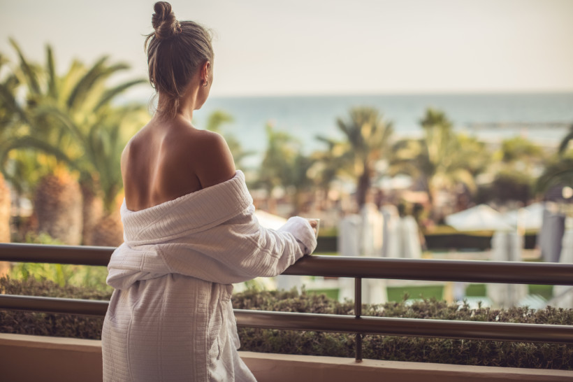 Entspannter Hotelurlaub auf Lanzarote – Komfort zum fairen Preis Frau im Bademantel auf einem Hotelbalkon mit Meerblick – Beispiel für komfortable Unterkünfte mit gutem Preis-Leistungs-Verhältnis auf Lanzarote.
