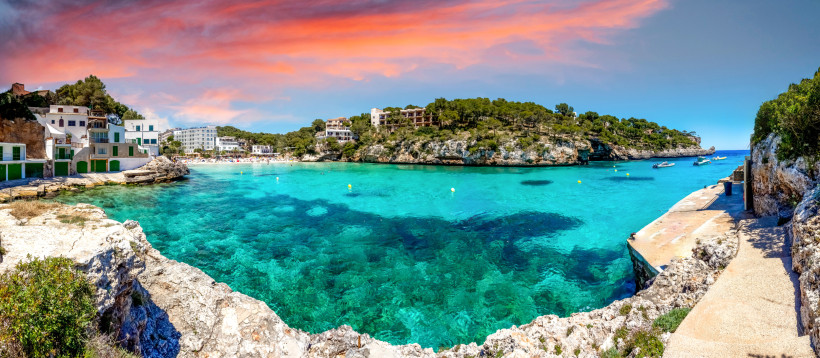 Cala Santanyí – Malerische Badebucht mit türkisblauem Wasser auf Mallorca Cala Santanyí Mallorca mit türkisblauem Wasser, Felsen, Fischerhäusern und Sandstrand bei Sonnenuntergang