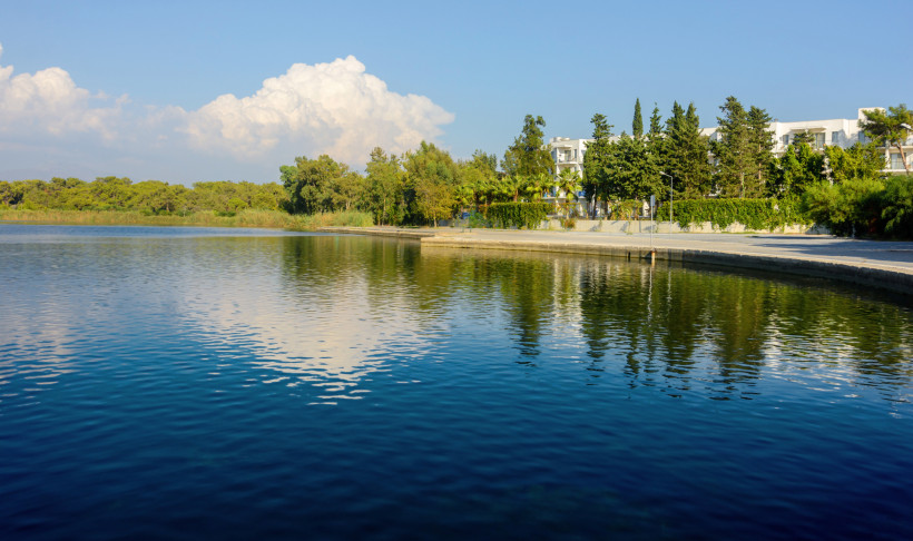 Titreyengöl in Side mit spiegelndem Wasser, Uferpromenade und Hotels im Hintergrund
