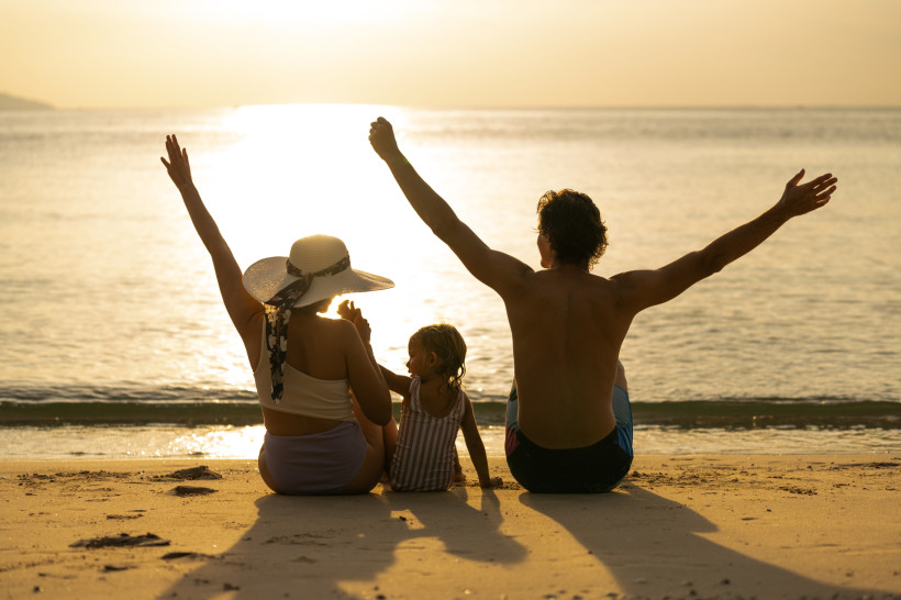 Familie sitzt am Strand bei Sonnenuntergang und blickt auf das Meer in Rethymno