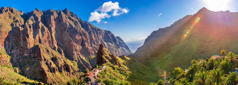 Panoramablick auf die Masca-Schlucht auf Teneriffa mit steilen Felsen, grüner Vegetation und Sonnenstrahlen
