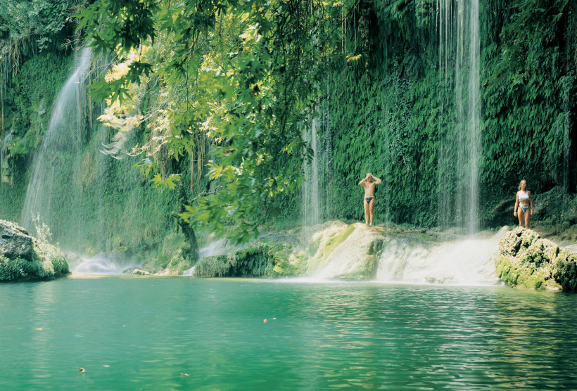 Kursunlu Wasserfall – Naturpool und Wasserfallidylle bei Antalya Menschen baden am Kursunlu Wasserfall nahe Antalya, umgeben von üppigem Grün, Felsen und einem smaragdgrünen Naturpool