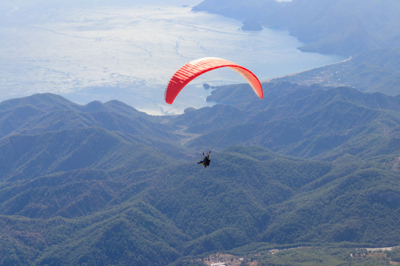 Aktive Paraglider schwebt über den Bergen bei Antalya mit Blick auf das Mittelmeer – Abenteuerurlaub für aktive Naturfans
