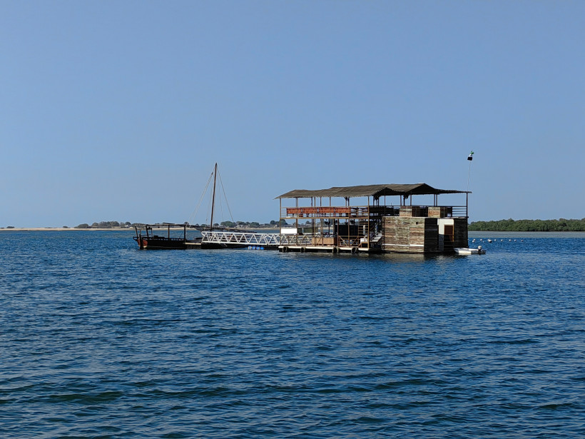 Schwimmendes Ponton der Suwaidi Pearl Farm in Ras Al Khaimah mit traditionellem Holzboot und Mangroven im Hintergrund.