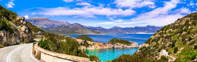 Kreta für Entdecker: Roadtrip - Blick auf eine Bucht mit türkisfarbenem Wasser und Berglandschaft Küstenlandschaft auf Kreta mit Bucht, türkisfarbenem Meer und Bergen unter blauem Himmel
