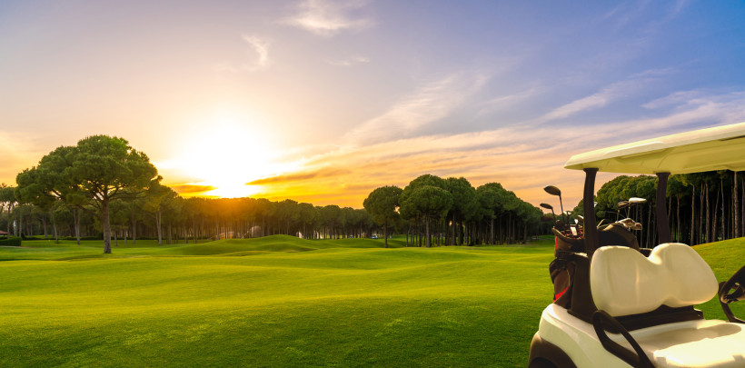 Golfplätze in Belek – Abschlag bei Sonnenuntergang am Spitzen-Golfresort Golfcart und gepflegte Fairways eines Golfplatzes in Belek bei goldenem Sonnenuntergang