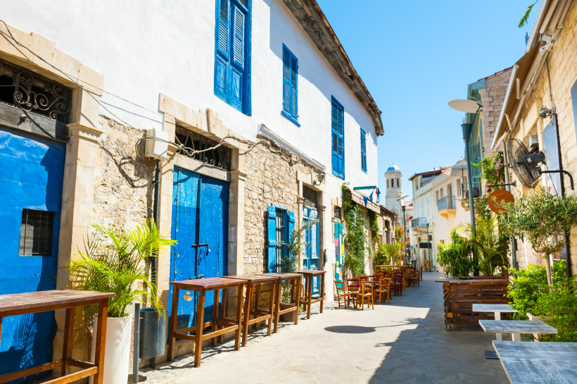 Enge Altstadtgasse in Limassol mit traditionellen Steinhäusern, blauen Türen und gemütlichen Straßencafés