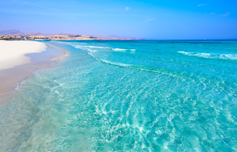 Sandstrand auf Fuerteventura mit türkisblauem Meer und flachem Wellengang