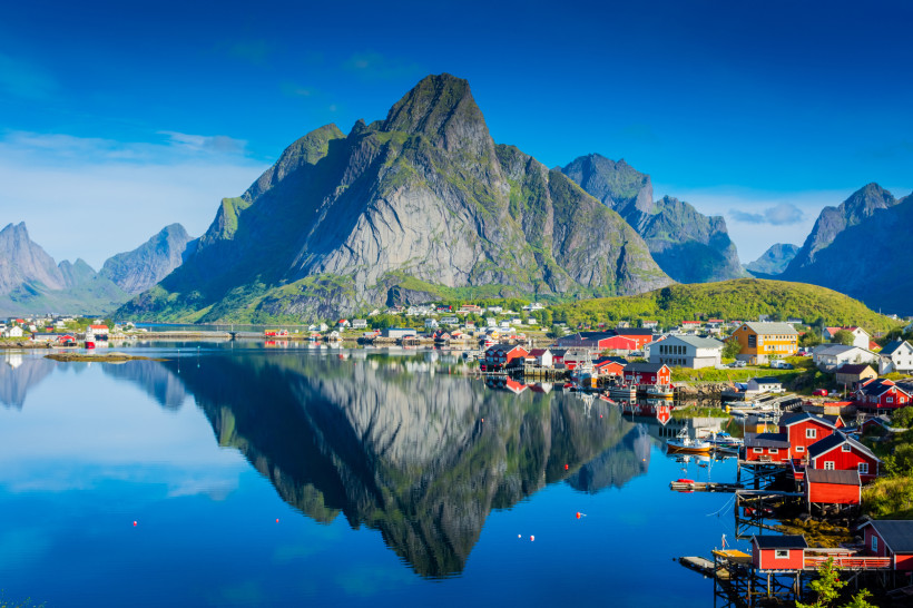 Reine auf den Lofoten mit Fjord, roten Häusern und Bergpanorama Berglandschaft auf den Lofoten mit Fischerdorf am Fjord und Spiegelung im ruhigen Wasser