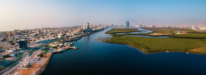 Luftaufnahme der Skyline von Ras Al Khaimah mit Mangroven, Wasserkanälen und moderner Corniche.