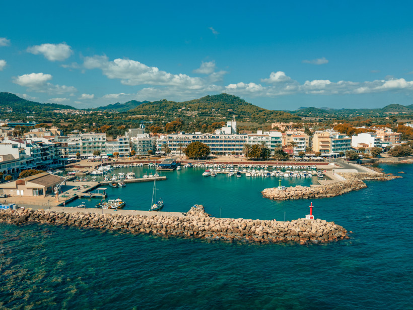 Luftaufnahme von Cala Bona mit Küstenlinie, Hotels und kleinem Hafen an Mallorcas Ostküste