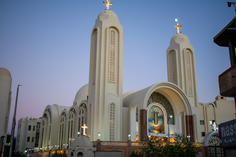 Koptische Kirche in Hurghada bei Sonnenuntergang mit hell beleuchteten Türmen und Kreuz