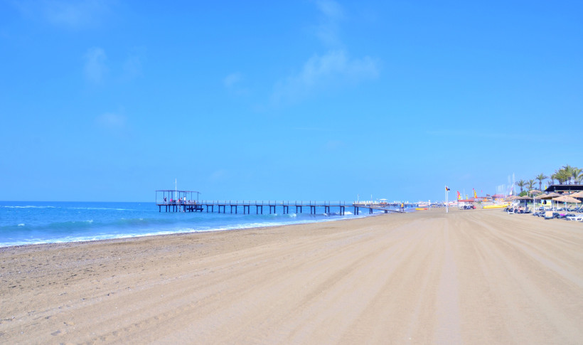 Reisetypen Belek – Weitläufiger Sandstrand und Steg an der Türkischen Riviera Breiter Sandstrand in Belek mit Holzsteg ins türkisfarbene Meer, ruhiger Küstenlinie und sonniger Atmosphäre – ideal für Paare, Familien und aktive Naturfans