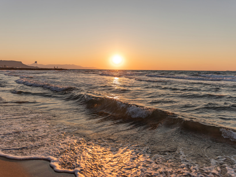 Sonnenuntergang über dem Meer bei Gouves mit sanften Wellen am Strand