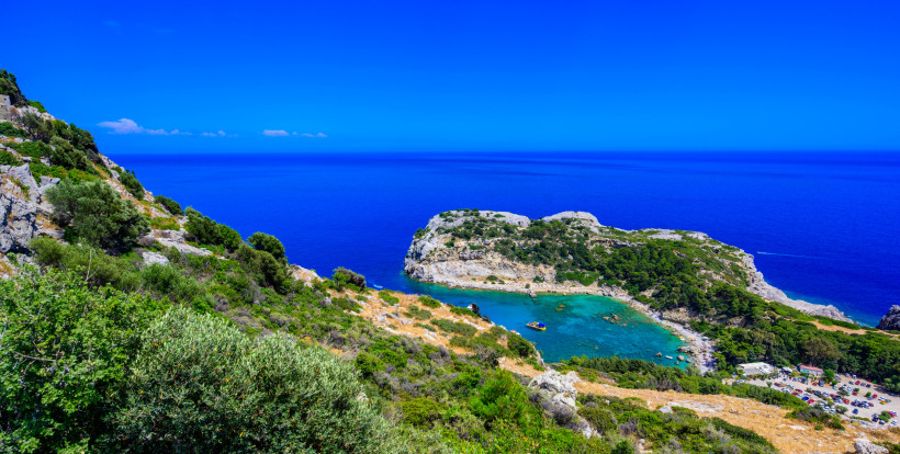 Traumhafte Badebucht auf Rhodos mit türkisblauem Wasser, felsiger Küste und grünen Hügeln