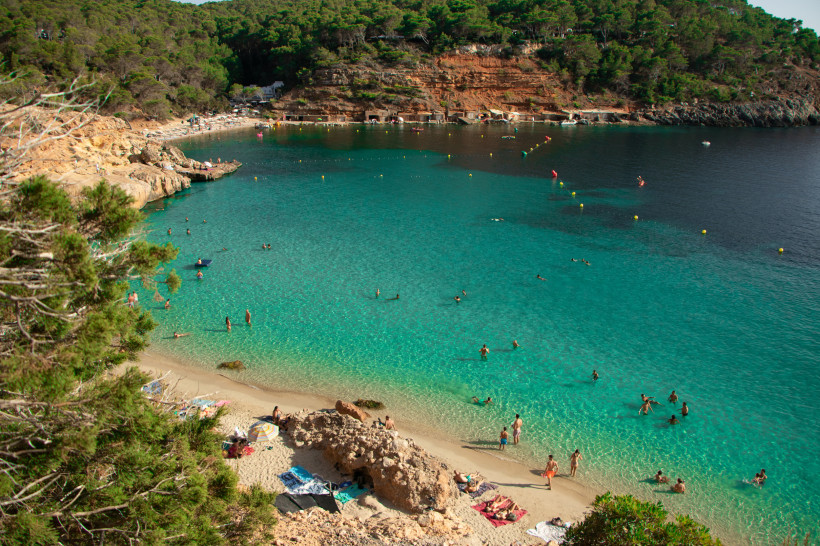 Badebucht Cala Salada auf Ibiza mit türkisfarbenem Wasser, Sandstrand und felsiger Küste