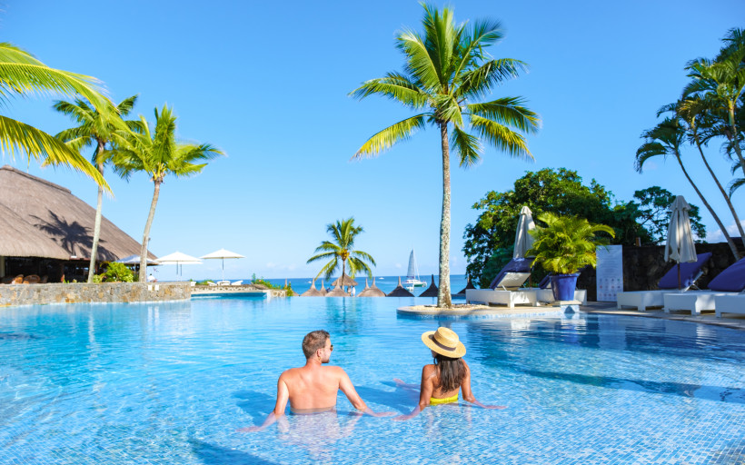 Paar entspannt im Infinity-Pool eines Adults-Only All-Inclusive-Resorts unter Palmen – romantischer Urlaub für Paare und Erwachsene