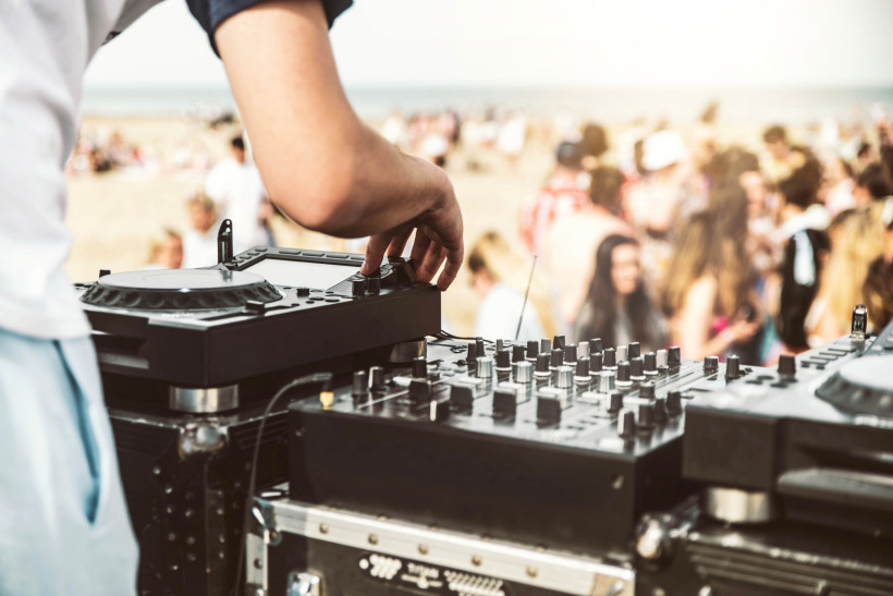 DJ-Pult mit Mischpult am Strand, Menschenmenge im Hintergrund, Playa d’en Bossa