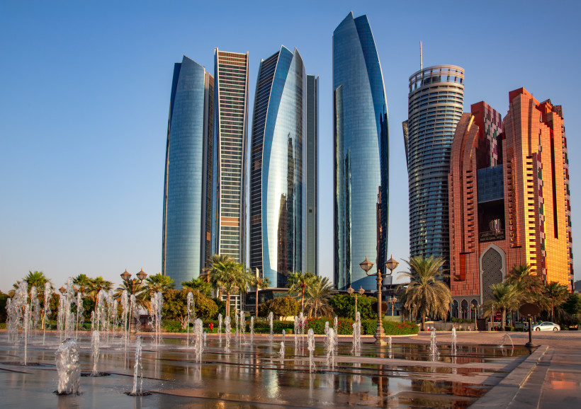 Die markanten, modernen Wolkenkratzer der Etihad Towers in Abu Dhabi, umgeben von Wasserfontänen und Palmen