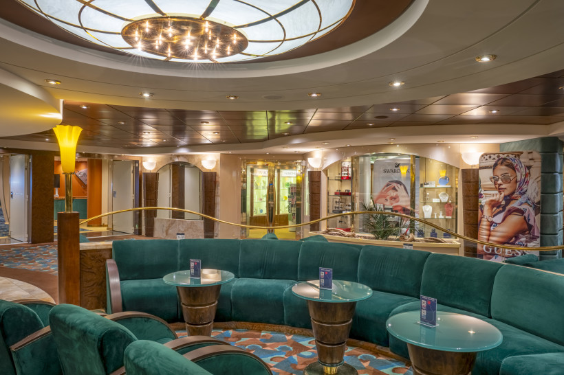 Sitzbereich der Amber Bar auf der MSC Orchestra mit runden Glastischen und türkisfarbenen Sofas