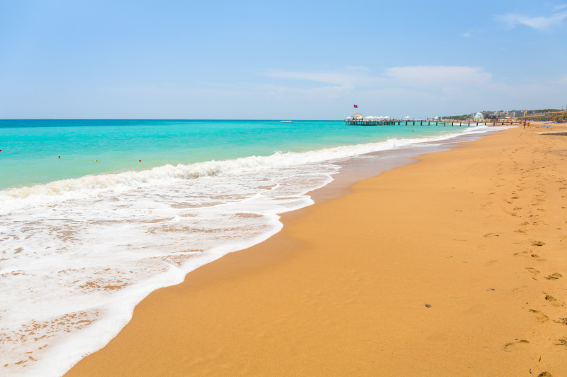 Sandstrand von Kumköy bei Side mit türkisblauem Meer und Badesteg