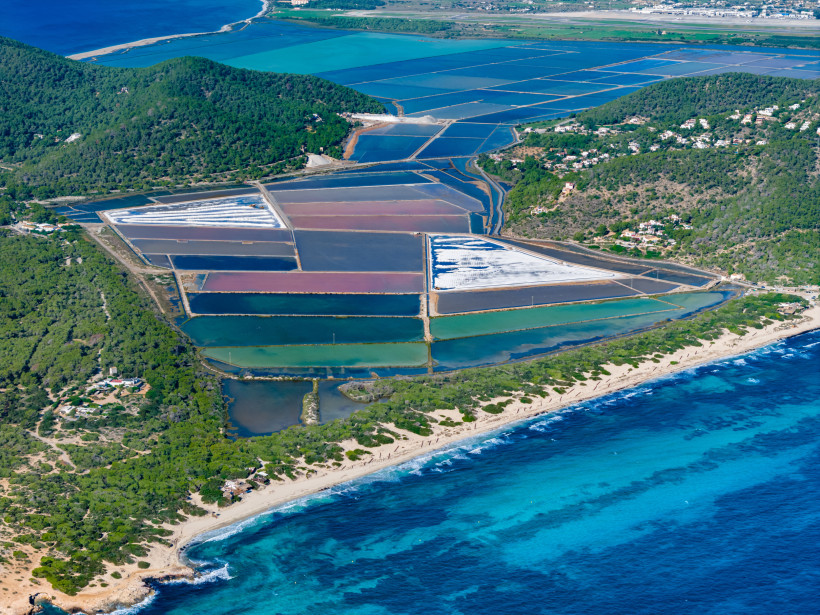 Luftaufnahme der Salinen im Naturpark Ses Salines auf Ibiza mit Salzbecken, Küstenlinie und türkisfarbenem Meer