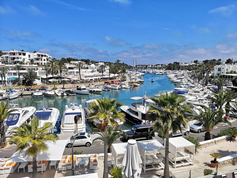 Yachthafen Port Esportiu in Cala d’Or mit zahlreichen Booten, Palmen, Restaurants und Flaniermeile direkt am Wasser