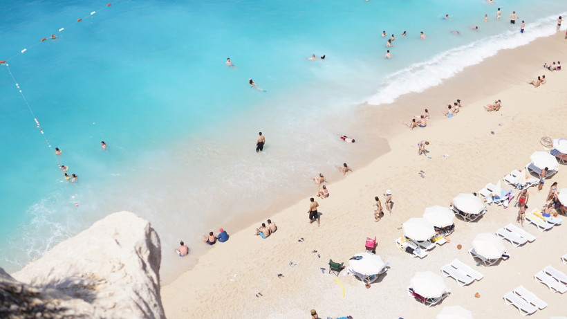 Feiner Sandstrand in der Region Antalya mit türkisblauem Wasser, Sonnenliegen und zahlreichen Badegästen – ideales Motiv für einen Strandurlaub an der Türkischen Riviera.