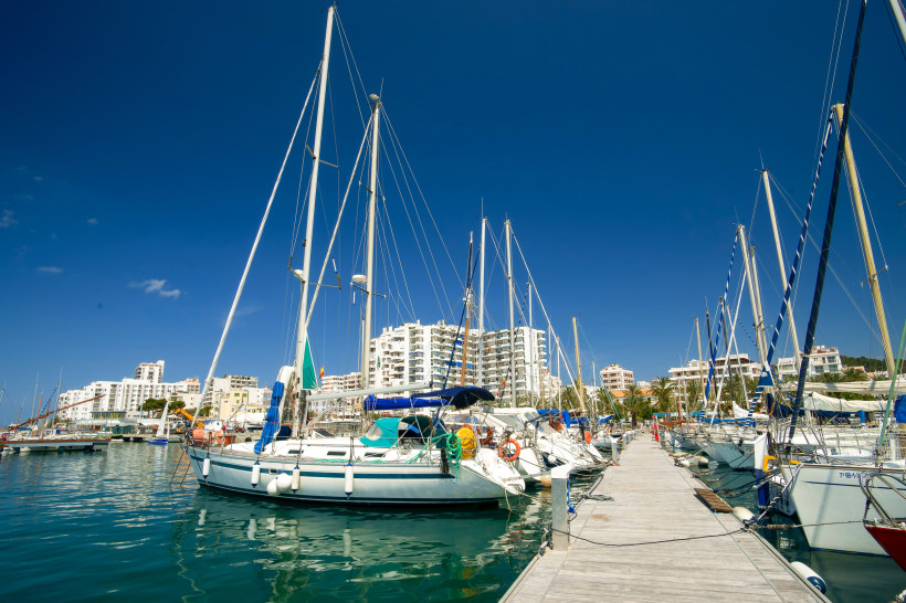 Segelboote im Hafen von Sant Antoni an einem Steg, im Hintergrund Wohngebäude