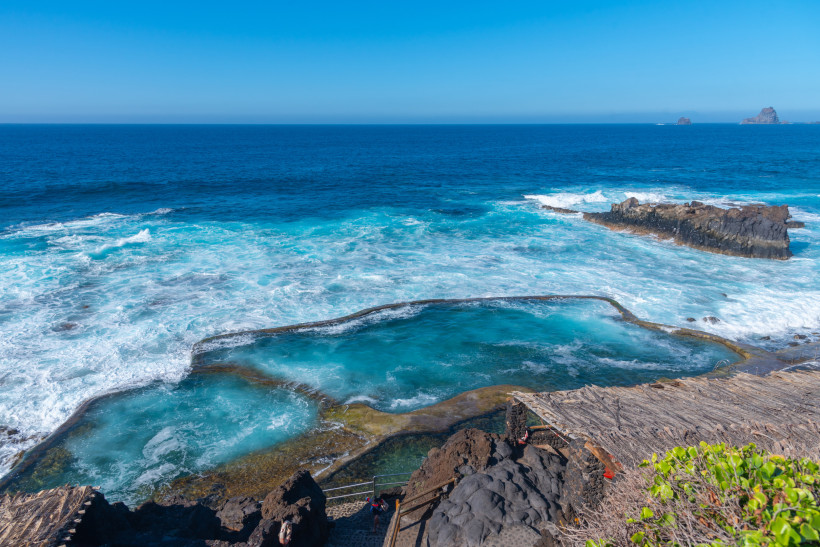 Natürlicher Meerwasserpool an der Felsküste von El Hierro mit Brandung und Blick auf den Atlantik