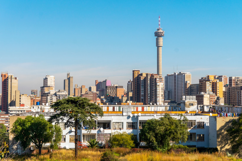 Skyline von Johannesburg mit dem Hillbrow Tower und Hochhäusern bei blauem Himmel